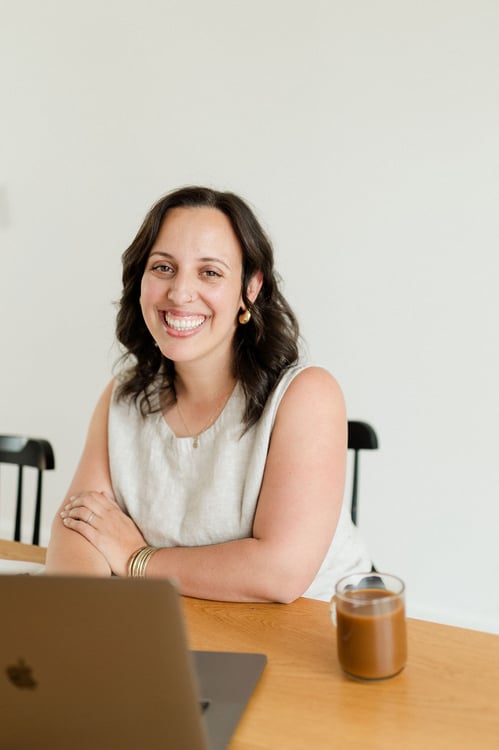 Soof sitting at a table, smiling, arms folded