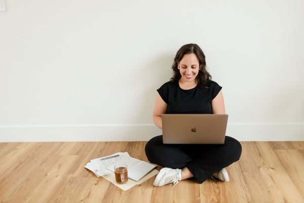 Soof sitting on the floor with her laptop, smiling