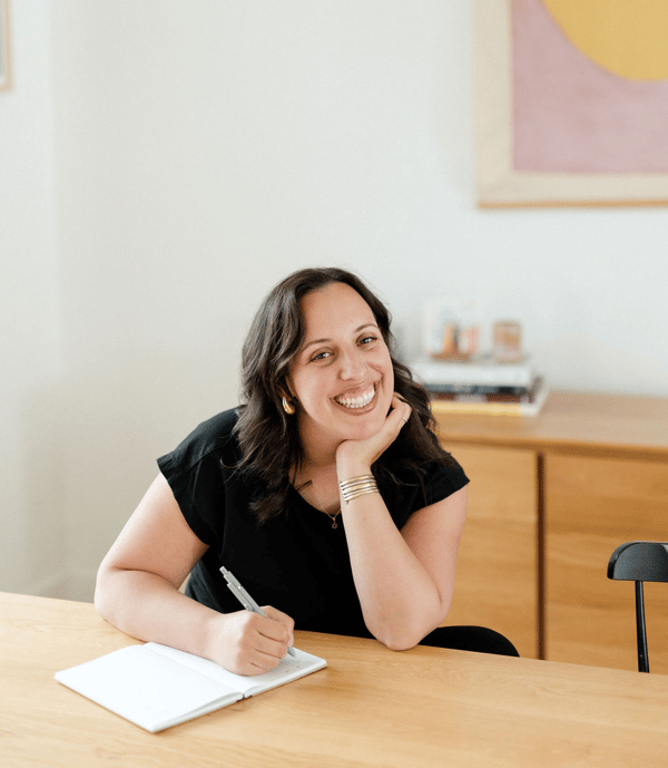 Soof smiling at her desk with a notebook